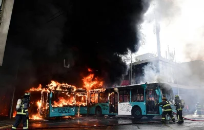 Chilean firefighters extinguish burning buses during clashes between protesters and the riot police in Santiago on October 19, 2019 /AFP