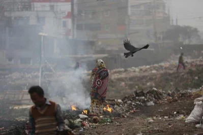 A woman stands by a garbage fire | Mahmud Hossain Opu/Dhaka Tribunen