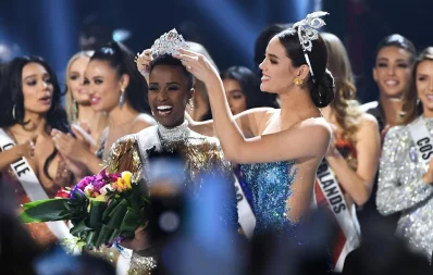 Miss Universe 2019 Zozibini Tunzi, of South Africa, is crowned onstage by Miss Universe 2018 Catriona Gray (R, in blue) at the 2019 Miss Universe Pageant at Tyler Perry Studios  in Atlanta, Georgia on December 08, 2019 AFP