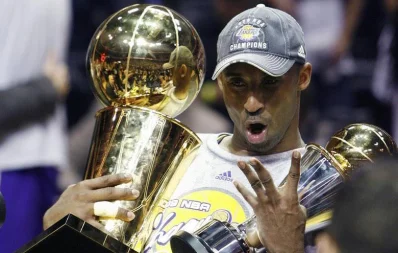 Kobe Bryant holds up the Bill Russell MVP Award (R) and the Larry OBrien Trophy as he signals his four career championship victories after they defeated the Orlando Magic to win the championship in Orlando, Florida on June 14, 2009 Reuters