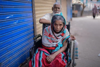 Sakhina Begum, brain stroke survivor, sits outside her home in Korail, her husband in attendance | Mahmud Hossain Opu/Dhaka Tribune