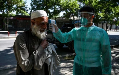 A health worker (R) checks the body temperature of a Muslim devotee as a preventive measure against the COVID-19 coronavirus at the start of the Eid al-Fitr festival which marks the end of the Muslim holy month of Ramadan at Wazir Akbar Khan mosque in Kabul on May 24, 2020 AFP
