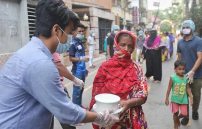 A volunteer hands over foods for iftar to a woman, under Dhaka Tribunes Share Your Meal initiative for the underprivileged people of Dhaka city, in Hazaribagh area on Sunday, May 17, 2020 Rajib Dhar/Dhaka Tribune