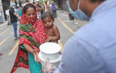 A volunteer hands over foods for iftar to a woman, under Dhaka Tribunes Share Your Meal initiative for the underprivileged people of Dhaka city, in Hazaribagh area on Sunday, May 17, 2020 Rajib Dhar/Dhaka Tribune