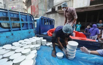 A volunteer hands over foods for iftar to a woman, under Dhaka Tribunes Share Your Meal initiative for the underprivileged people of Dhaka city, in Hazaribagh area on Sunday, May 17, 2020 Rajib Dhar/Dhaka Tribune