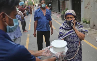 A volunteer hands over foods for iftar to a woman, under Dhaka Tribunes Share Your Meal initiative for the underprivileged people of Dhaka city, in Hazaribagh area on Sunday, May 17, 2020 Rajib Dhar/Dhaka Tribune