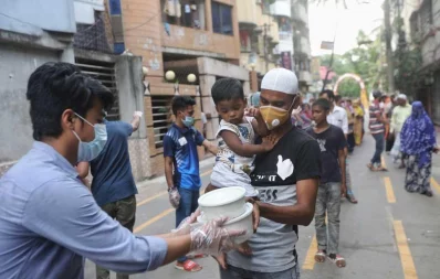 A volunteer hands over foods for iftar to a woman, under Dhaka Tribunes Share Your Meal initiative for the underprivileged people of Dhaka city, in Hazaribagh area on Sunday, May 17, 2020 Rajib Dhar/Dhaka Tribune