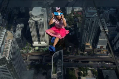 A girl observes a partial solar eclipse on the Mahanakhon Skywalk Glass Tray at the King Power Mahanakhon building in Bangkok, Thailand, June 21, 2020 Reuters