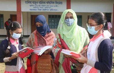 Two students of Halima Khatun Girlsu2019 High School take a look at their new textbooks on Friday, January 1, 2021 Dhaka Tribune