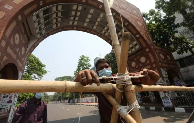 A volunteer uses bamboo to construct a barrier at the entrance of Dhaka University campus at Nilkhet area on the first day of the week-long lockdown on Monday Mahmus Hossain Opu/Dhaka Tribune