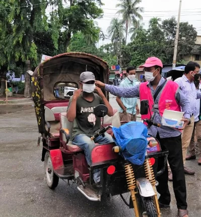 BRAC volunteer is distributing free masks in a public hotspot to reinforce mask wearing habitsn