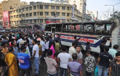  People stand near the torched bus in Gulistan, Dhaka on Monday, November 6, 2023. Photo: Mehedi Hasan/Dhaka Tribune