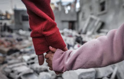 People hold hands as they inspect the damage on buildings destroyed during Israeli bombardment in Rafah on the southern Gaza Strip on December 29, 2023, amid the ongoing battles between Israel and the Palestinian group Hamas. Photo: AFP