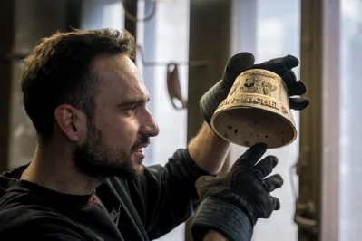 Alois Huguenin holds a freshly crafted bell in his foundry