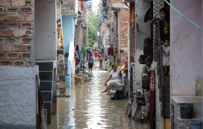 Residents sit outside their flooded houses after a breach in a canal that supplies water from a nearby state, in New Delhi on July 11, 2024.