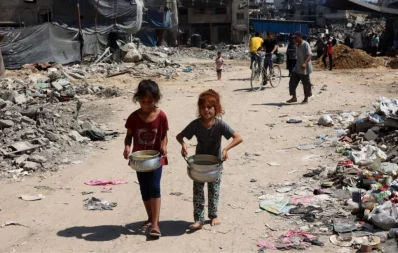 Palestinian children carry pots of soup near a food distribution point in the Jabalia refugee camp in northern Gaza Strip on August 21, 2024. Photo: AFP