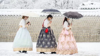 Visitors wearing traditional hanbok dresses are seen on the grounds of Gyeongbokgung Palace amid heavy snowfall in central Seoul on November 27, 2024. Photo: AFP