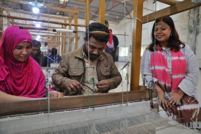 A visitor admiring the magic of artisans weaving muslin in a loom at the House of Dhaka Muslin. Photo: Dhaka Tribune
