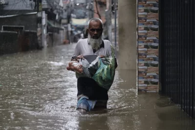 A resident carries groceries through floodwater in Karwan Bazar as persistent monsoon rain inundates roads and surrounding areas, forcing people to wade through water to meet their daily needs in Dhaka on Sunday. Photo: Abir Ahmmed Shupto/Dhaka Tribune