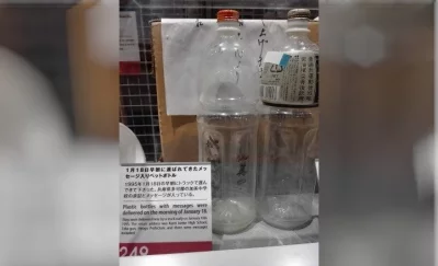 The image shows a memorial exhibit featuring plastic bottles with messages that were delivered on January 18, 1995, just one day after the devastating earthquake. According to the exhibit sign, these bottles were delivered by truck from Kami Junior High School in Taka-gun, Hyogo Prefecture. They contain messages of support and encouragement for the survivors of the disaster.