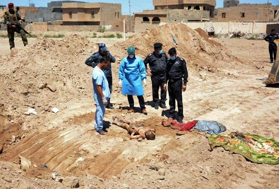 In this April 19, 2016 file photo, an Iraqi security forces forensic team works at the site of a mass grave believed to contain the bodies of Iraqi civilians, security forces and members of their families, including women and children, killed by Islamic State group militants at the stadium area in Ramadi, Iraq AP