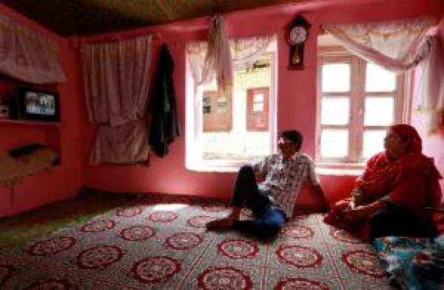 Members of a family watch television in their home in Srinagar as the city remains under curfew following weeks of violence in Kashmir REUTERS