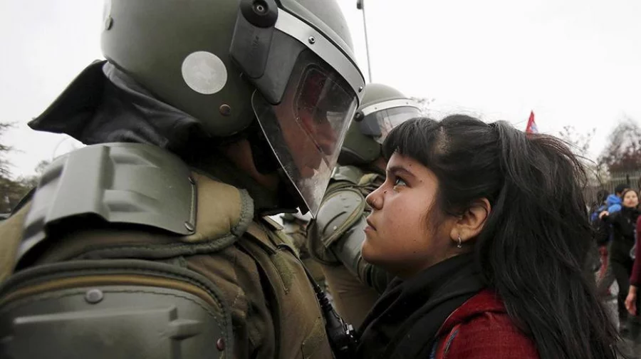 A demonstrator stares at a riot policeman during a protest marking Chile’s 1973 military coup in the capital, Santiago/Reuters