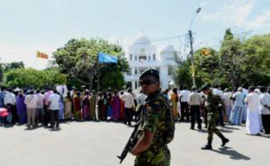 Soldiers atand alert as Sri Lankan mothers from the 'Missing Person's Parents' join others as they hold photographs during a protest outside the Jaffna Library in Jaffna,some 400 kilometres (250 miles) north of Colombo on September 2, 2016. UN Secretary-General Ban Ki-moon has toured Sri Lanka's former killing fields and met with war-battered minority Tamils after urging Colombo to reduce the army's presence to ease tensions following decades of ethnic bloodshed.The UN Secretary-General held talks with the main opposition politicians in the northern town of Jaffna, 400 kilometres (250 miles) north of Colombo on the final leg of the two day visit. / AFP PHOTO / ISHARA S.KODIKARA