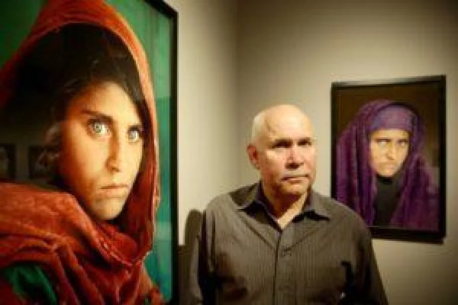  US photographer Steve McCurry poses next to his photos of the "Afghan Girl" named Sharbat Gula at a 2013 exhibition in Hamburg, northern Germany