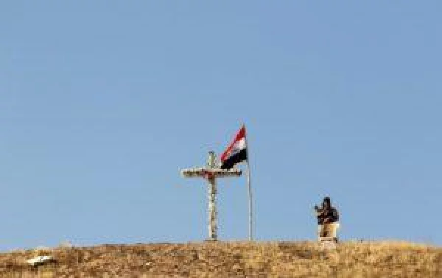 An Iraqi forces member patrols next to a cross with flowers on close to the Saint Barbara Church on October 30, 2016 in the town of Qaraqosh (also known as Hamdaniya), 30 kms east of Mosul, after Iraqi forces recaptured it from Islamic State (IS) group jihadists. Iraqi forces are fighting their way toward Mosul to retake it from IS in an operation that is now in its second week, and some Christian villages have already been retaken. / AFP PHOTO / SAFIN HAMED