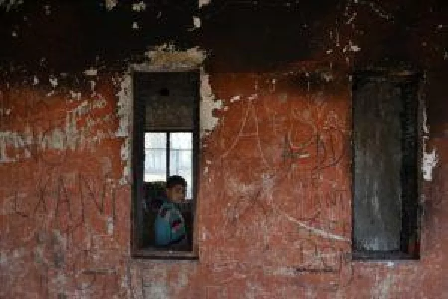 A Kashmiri student looks out of a window of a partially burnt government high school in Goripora, on the outskirts of Srinagar on November 2, 2016. Hundreds of schools were ordered to close indefinitely in Kashmir, November 2, 2016 after shelling by Indian and Pakistani troops in the disputed region killed 14 civilians in two days. Nearly 30 schools have been torched in the Kashmir Valley since July but there have yet to be any arrests for the arson attacks. / AFP PHOTO / TAUSEEF MUSTAFA