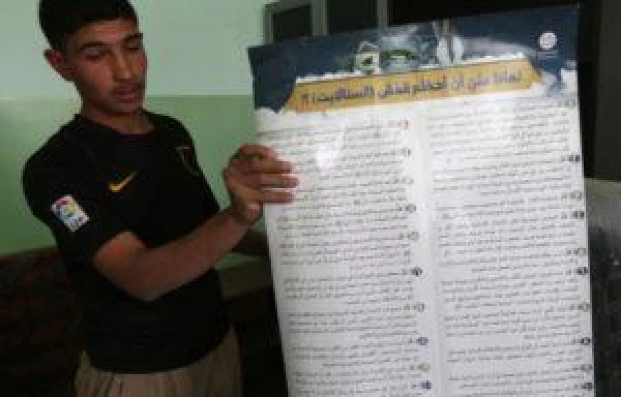 An Iraqi youth shows a placard printed out by the Islamic State (IS) group, explaining why people shouldn't use satellite dishes, as he visits his school in the village of Jarif, some 45 kilometres south of Mosul, on November 12, 2016, after Iraqi forces retook it from IS jihadists. / AFP PHOTO / SAFIN HAMED
