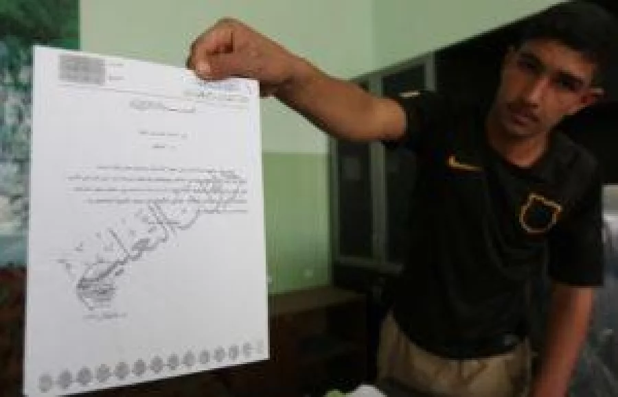 An Iraqi youth shows a document issued by the education office of the Islamic State (IS) group as he visits his school in the village of Jarif, some 45 kilometres south of Mosul, on November 12, 2016, after Iraqi forces retook it from IS jihadists. / AFP PHOTO / SAFIN HAMED