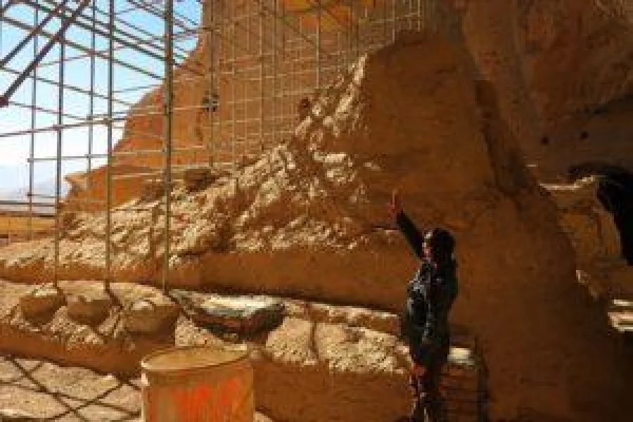 This picture taken on November 6, 2016 shows Afghan archeological guard, Hakim Safam standing in front of the reconstructed foot of the Salsal Buddha, which was 58 metres high before being destroyed by the Taliban in 2001, in Bamiyan province. remains of the Buddha statues which were destroyed by the Taliban in 2001, are kept by UNESCO on the site in Bamiyan province.    For centuries they stood, two monumental ancient statues of Buddha carved into the cliffs of Bamiyan, loved and revered by generations of Afghans --  only to be pulverised by the Taliban in an act of cultural genocide. / AFP PHOTO / ANNE CHAON / TO GO WITH AFP STORY: 'Afghanistan-Unrest-Archaeology-Culture-Buddhas' ; Feature by Anne CHAON