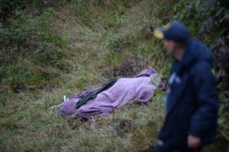 A rescuer walks past the body of a victim from the LAMIA airlines charter plane crash in the mountains of Cerro Gordo, municipality of La Union, on November 29, 2016. A charter plane carrying the Chapocoense Real football team crashed in the mountains in Colombia late Monday, killing as many as 75 people, officials said.  / AFP PHOTO / Raul ARBOLEDA