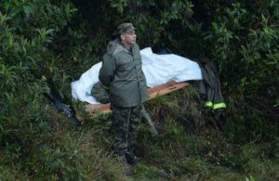 A police officer stands next to the body of a victim of the LAMIA airlines charter plane crash in the mountains of Cerro Gordo, municipality of La Union, on November 29, 2016. A charter plane carrying the Chapecoense Real football team crashed in the mountains in Colombia late Monday, killing as many as 75 people, officials said.  / AFP PHOTO / RAUL ARBOLEDA
