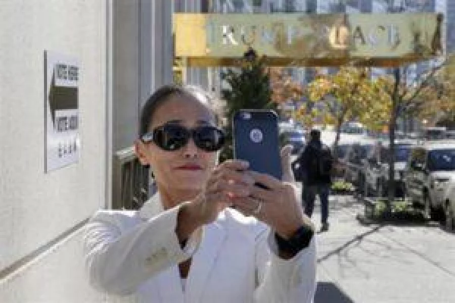 In this Nov. 8, 2016 file photo, a woman takes a selfie outside a polling place after voting in an apartment building named for Republican presidential candidate Donald Trump in New York. The luxury apartment building is one of three that will have the president-elect's name stripped from it after hundreds of residents signed an online petition demanding it be removed. (AP Photo/Richard Drew)