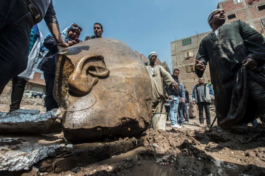 Egyptian minister of antiquates Khaled el-Anani poses for picture with workers next to the head of a statue at the site of a new discovery by a team of German-Egyptian archeologists in Cairo's Mattarya district on March 9, 2017. Statues of the kings and queens of the nineteenth dynasty (1295 - 1185 BC) were unearthed in the vicinity of the Temple of Ramses II in what was the old Pharonic city.  KHALED DESOUKI / AFP   Add to cart Print