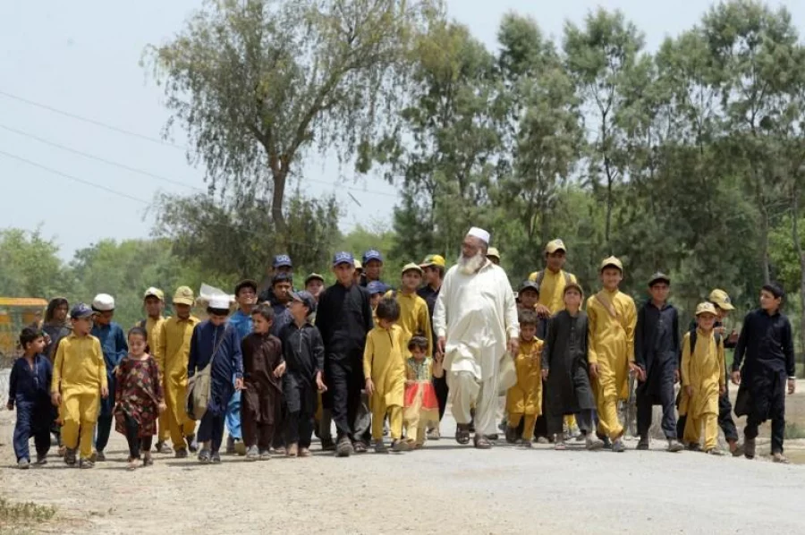 In this photograph taken on May 20, 2017, Pakistani father Gulzar Khan, 57, who has 36 children from his three wives, walks with his children as they return home after school in the northwestern town of Bannu. Three men who have fathered nearly 100 children among them are doing their bit for Pakistan's skyrocketing population, which is being counted for the first time in 19 years. Pakistan has the highest birth rate in South Asia at around three children per woman, according to the World Bank and government figures, and the census is expected to show that growth remains high. / AFP PHOTO / ABDUL MAJEED / TO GO WITH AFP STORY PAKISTAN-CENSUS-POPULATION-SOCIAL,FOCUS BY MAAZ KHAN AND SAJJAD TARAKZAI