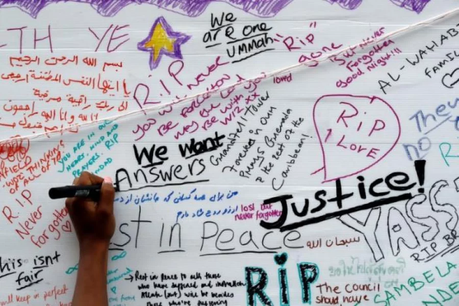 A woman writes on a message wall near the scene of the fire which destroyed the Grenfell Tower block, in north Kensington, West London, Britain June 15, 2017 REUTERS/Stefan Wermuth