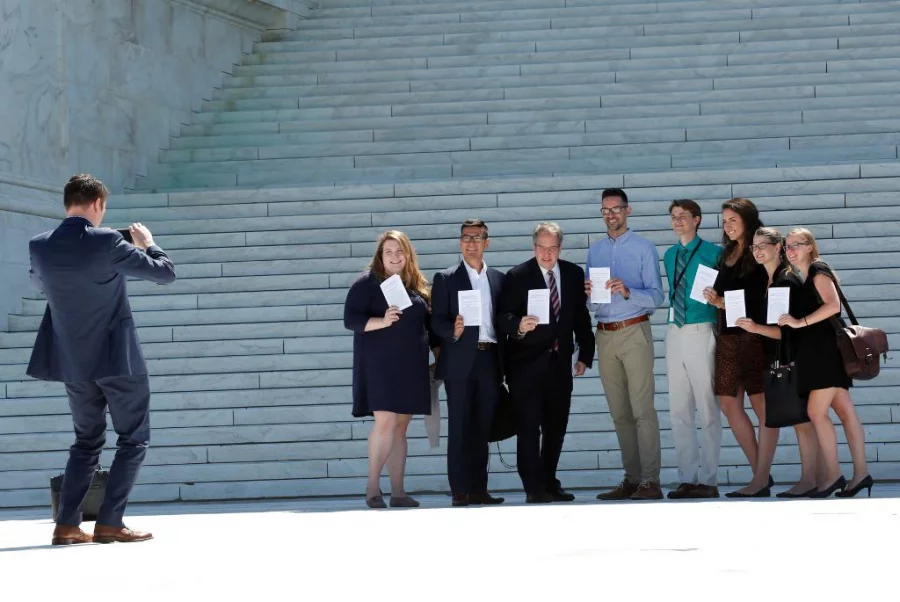 People pose for a group photo with the US Supreme Court's papers after the Court granted parts of the Trump administration's emergency request to put his travel ban into effect immediately while the legal battle continues, in Washington, US, June 26, 2017 REUTERS