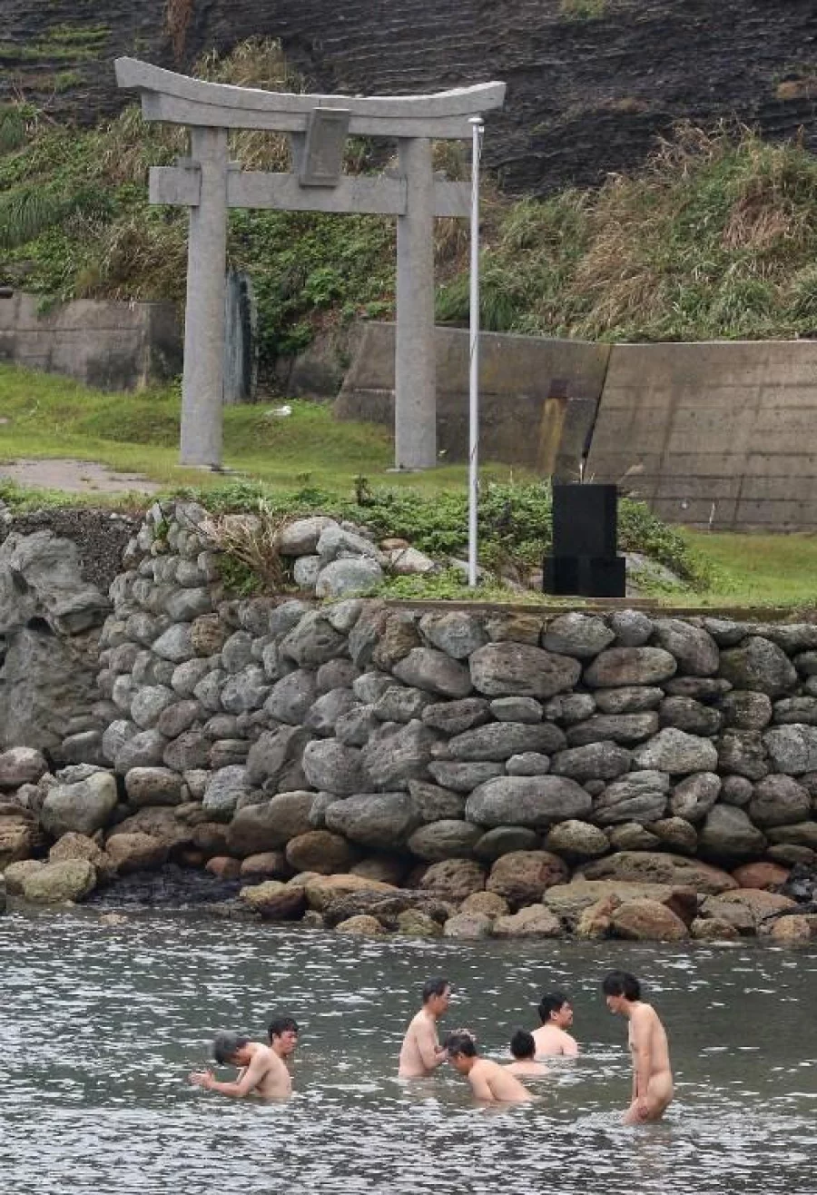 This September 30, 2016 picture shows devotees purifying themselves with sea water before entering Okinoshima island, some 60km from Munakata city, Fukuoka prefecture. The island of Okinoshima and associted sites in the Munakata Region have been inscribed at the 41st session of the UNESCO World Heritage Committee held in Poland on July 9, 2017. / AFP PHOTO / JIJI PRESS / STR / Japan OUT