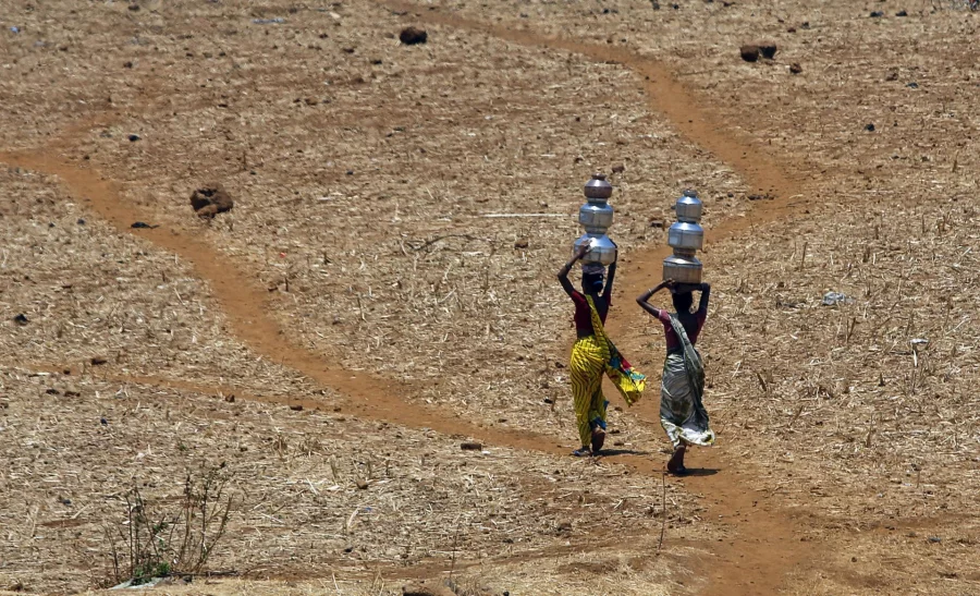 FILE - In this May 4, 2016 file photo, Indian women walk home after collecting drinking water from a well at Mengal Pada in Thane district in Maharashtra state, India, after a heatwave and severe drought conditions struck the region. A report by the Asia Development Bank on Friday, July 14, 2017, says Asia will endure extreme heat, rising sea levels, growing losses from severe weather and increasing food insecurity in coming decades as climate change raises temperatures and alters weather patterns across the globe. (AP Photo/ Rajanish Kakade, File)