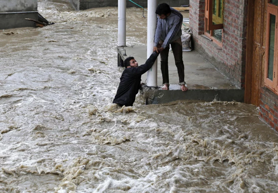 In this March 30, 2015 file photo, a Kashmiri man stretches his hand to help a local evacuate from a flood affected area in Srinagar, Indian-controlled Kashmir. A report by the Asia Development Bank on Friday, July 14, 2017, says Asia will endure extreme heat, rising sea levels, growing losses from severe weather and increasing food insecurity in coming decades as climate change raises temperatures and alters weather patterns across the globe. (AP Photo/Mukhtar Khan, File)