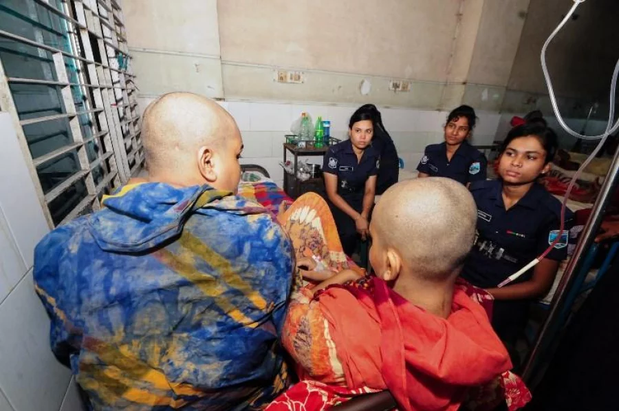 A rape victim (R) and her mother lay in a stretcher next to Bangladeshi police for protection at a Hospital in Bogra on July 30, 2017. Bangladesh police have arrested four men over the rape of a teenager whose head was shaved as punishment by the accused's wife in a case that has shocked the conservative country, an official said July 30 AFP 
