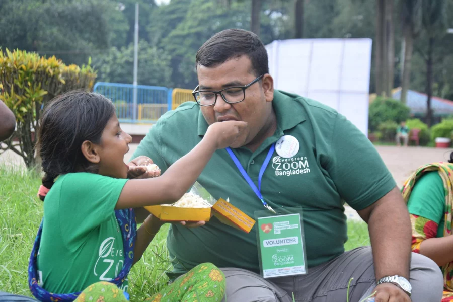 A beautiful image of a child a volunteer sharing their meal at the event | Evergreen Zoom Bangladesh Foundation 
